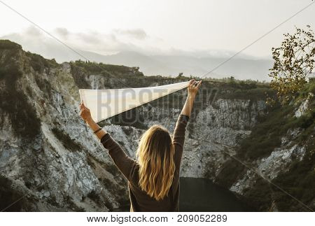 Woman arms raised and holding flag on mountain