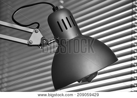 Closeup of a desk lamp and sunblind in black and white colors