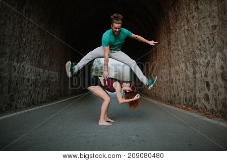 Man leapfrog jumping over woman on a road