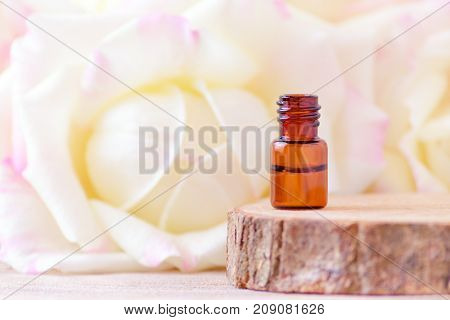 rose essential oil in a glass bottle with fresh rose flowers, nature background