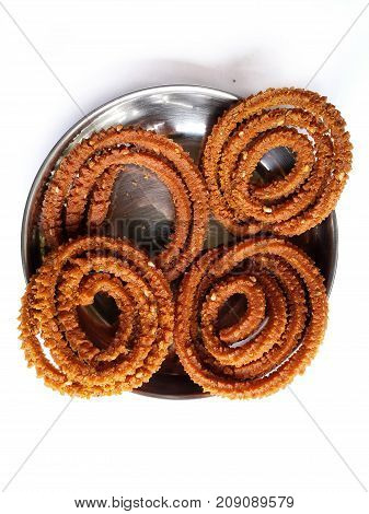 Diwali festival refreshment snacks chakali or murukku in steel plate closeup shot from above with selective focus