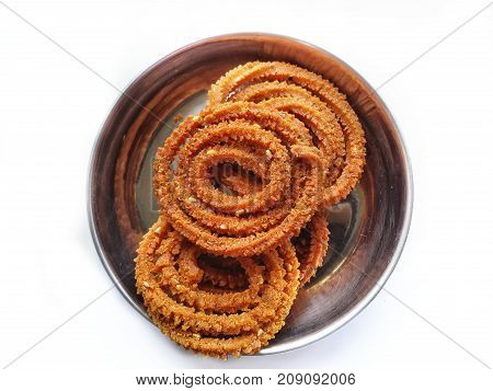 Chakali or murukku,diwali festival refreshment snacks in steel plate isolated on white background