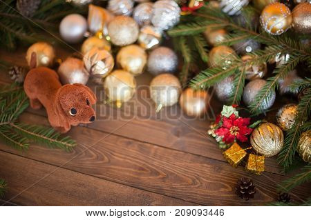 Year of the dog. Dog with a gift on a wooden background. Christmas balls pine cones a composition of the new year in golden color. The year of the dog on a horoscope symbol. Copyspace emptu space for text.