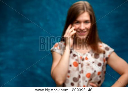 Blurred image of Happy cheerful female looking at the camera and talking on the mobile phone. Portrait of beautiful smiling caucasian woman using her smartphone. Copy Space.