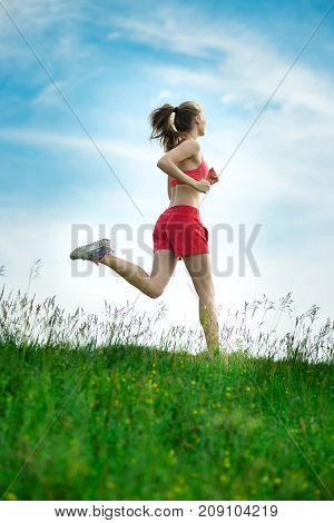 Young lady running. Woman runner running through the summer park rural road. Workout in a park. Beautiful fit girl. Fitness model caucasian ethnicity outdoors. Weight loss exercise. Jogging.