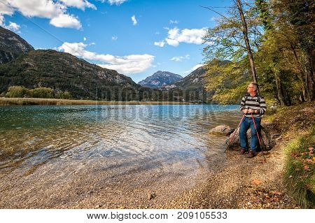 Hiker Sitting On A Rock By The Lake.