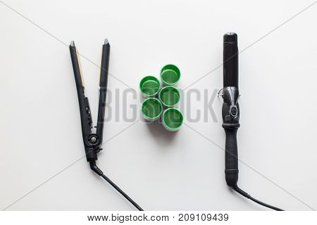 hair tools, beauty and hairdressing concept - curling iron, hot styler and curlers on white background