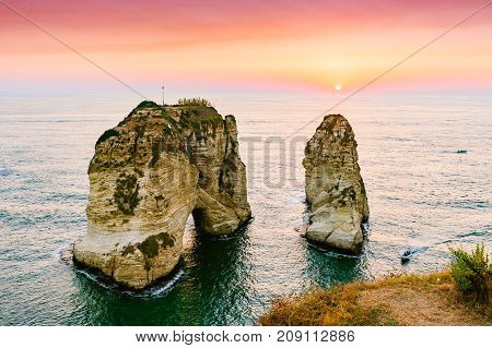 Beautiful sunset on Raouche, Pigeons' Rock. In Beirut, Lebanon.Sun and Stones are reflected in water.dense clouds in the sky.