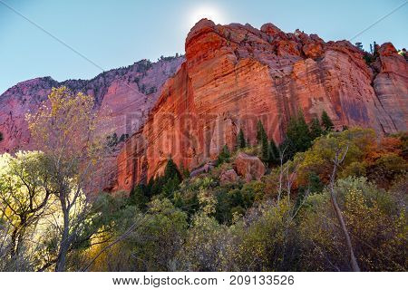 Trail view in Kolob Canyon part of Zion National Park in the autumn with the sun peeking behind a cliff.