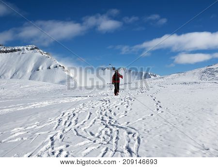 Skier with skis on his shoulder go up to top of mountain in nice sun day. Caucasus Mountains in winter Georgia region Gudauri Mt. Kudebi.