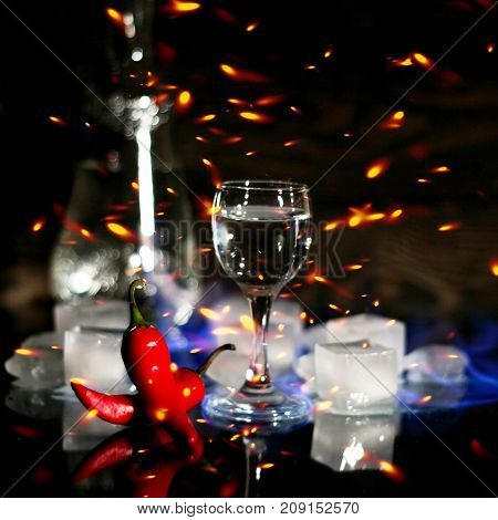 A Shot Of Vodka, An Alcoholic Beverage, Next To Ice, Fire, Ice, Red Chili Pepper. The Concept Of Alc