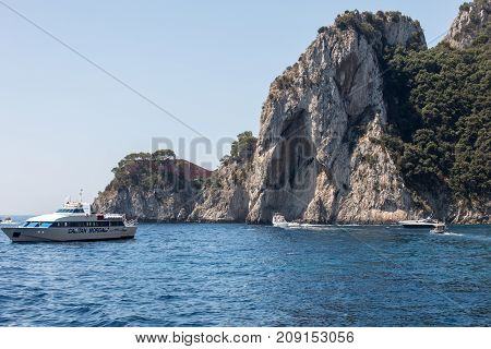 CAPRI ITALY - JUNE 13 2017: View from the boat on the Boats with tourists and the cliff coast of Capri Island. Italy