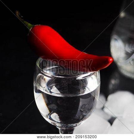 A Shot Of Vodka, An Alcoholic Beverage, Next To Ice, Fire, Ice, Red Chili Pepper. The Concept Of Alc
