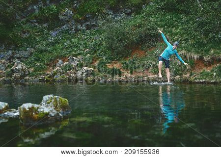 a woman tourist stands on the Bank of the mountain lake with turquoise water. Glanni waterfall, Iceland, woman tries to go into cold water