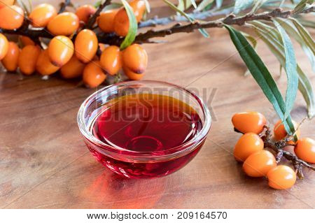 Sea Buckthorn Oil In A Glass Bowl With Sea Buckthorn Branches