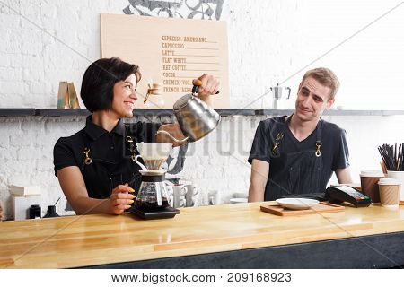 Coffee business backgroung with copy space. Portrait of two young bartenders preparing fresh pourover coffee at cafe bar counter. Occupation people and service concept