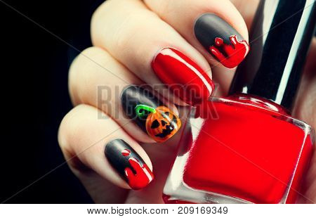 Halloween manicure design ideas. Halloween Nail art design. Nail Polish. Beauty Trendy Stylish Colorful Nails and Nailpolish. Black matte nailpolish with blood drips and pumpkin. Isolated on black