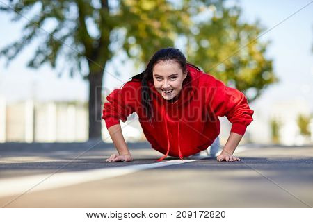 Lovely girl in red uniform girl squeezes off the floor in the street