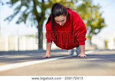 Lovely girl in red uniform girl squeezes off the floor in the street