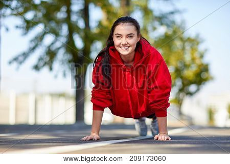 Lovely girl in red uniform girl squeezes off the floor in the street