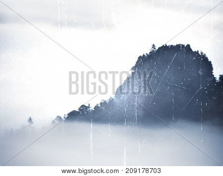 View Into Misty Valley. High Trees And Rocky Peaks Increased From Thick Fog.  The First Sun Rays Cre