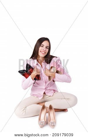 A beautiful girl with dark long hair holds a pair of heels in hands. Three pairs of high-heeled patent shoes isolated on a white background. Close-up of shoes. Fashion concept.