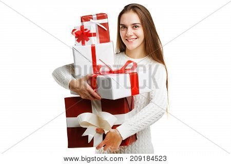 Beautiful smiling girl with a long hair posing on the camera in studio and holding christmas gift isolated on white background. Close-up of gifts. Holiday concept.