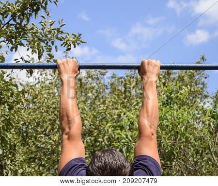 Hands On The Bar Close-up. The Man Pulls Himself Up On The Bar.