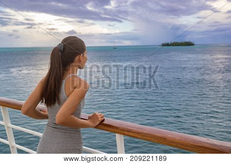 Luxury cruise vacation woman looking at French Polynesia motu island from boat deck at sunset. Elegant tourist relaxing at view of ocean scenery at dusk, relaxing outdoor. Sailing lifestyle holidays.