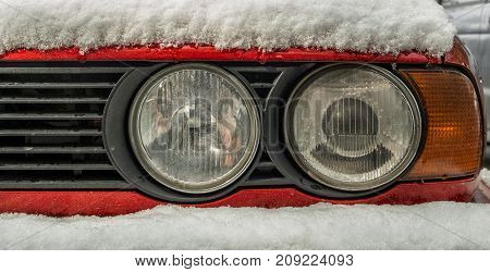 Car headlight closeup. Detail of the old car exterior. Old car headlight. Car covered with snow