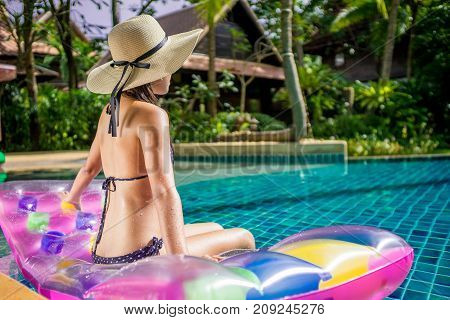 Women wearing bigini or swimware suits swimming pool sitting on a blue protrude at the resort town of Pattaya in Thailand.