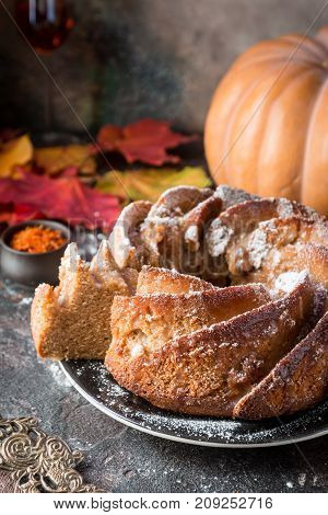Bundt cake with saffron and rum covered with white glaze on rustic background with autumn decorations