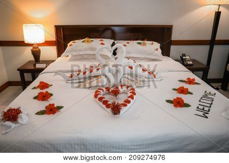 Bed decorated with flowers and towels in hotel room