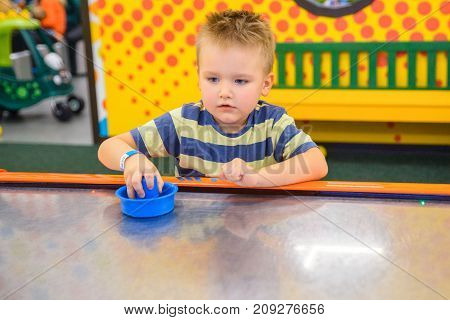 little kid plays in air hokey in Entertainment Center