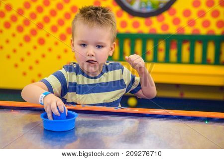 little kid plays in air hokey in Entertainment Center
