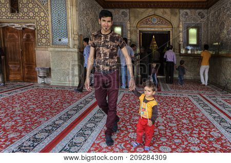 Fars Province Shiraz Iran - 19 april 2017: Shah Cheragh Shrine A man leaves the mosque after a prayer and holds the hand of a small child.