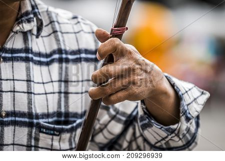 man plays an erhu, two-stringed bowed fiddle. The Erhu is an ancient Asian instrument, brought to China 140 B.C.