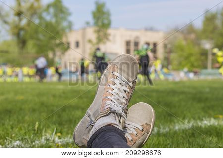 Close up of female watching football game: snickers shoes on background of American football match