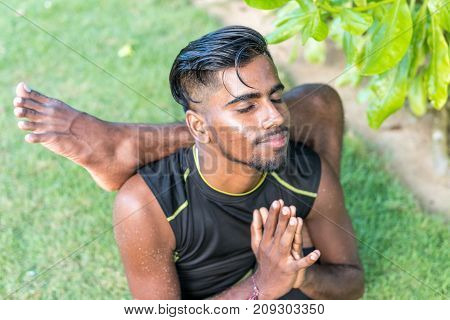 Young yoga man practitioners doing yoga on nature. Asian indian yogis man on the grass in the park.