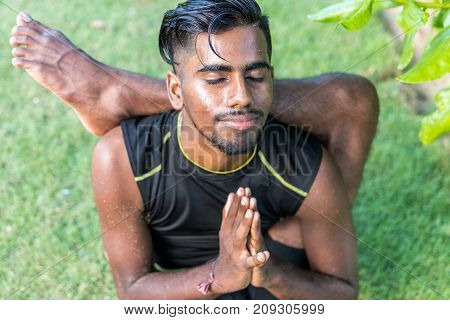 Young yoga man practitioners doing yoga on nature. Asian indian yogis man on the grass in the park.