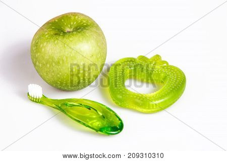 baby teeth care. green composition of apple toothbrush and teethers