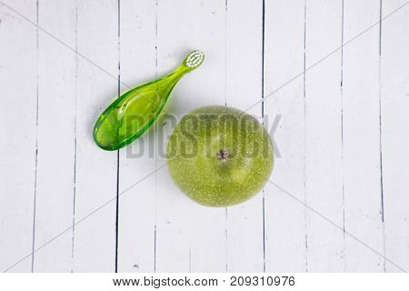 baby teeth care. green composition of toothbrush and teether on a light wooden background