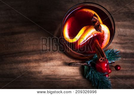 Christmas Hot mulled wine for winter with spices and orange slices on rustic table with copy space. Red Hot wine or gluhwein with Christmas Decorations on wooden background close up