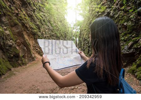 Back side of young traveler see the map in the deep forest Hellfire Pass at kanchanaburi Thailand Travel and transportation concept