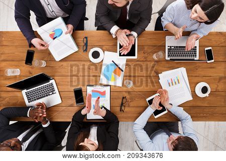 Multiethnic business meeting. Employees clapping hands cheering successful reporter top view of wooden table