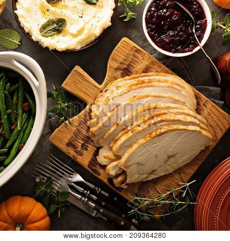 Sliced roasted tukey breast for Thanksgiving or Christmas dinner with side dishes overhead shot