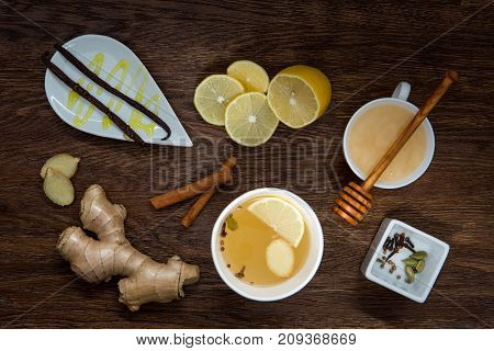 Winter hot drink and spices. Cup of tea , lemon, ginger, honey and cinnamon on wooden table. anti-cold products. Top view