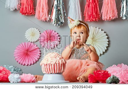 Little baby girl eating birthday cake during cake smash party