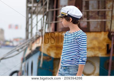 Portrait of a boy in a striped long sleeve T-Shirt (Telnyashka) and captain's cap.
