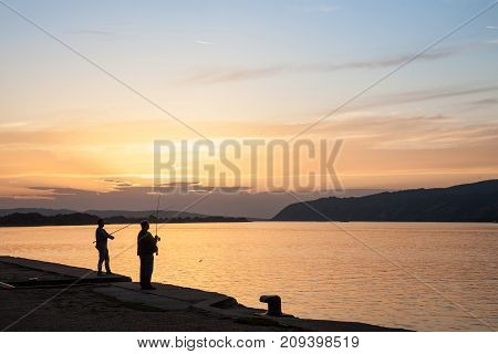 VELIKO GRADISTE SERBIA - SEPTEMBER 16 2017: Fishermen fishing on the quay of Veliko Gradiste at Sunset on the Danube river Picture of two men fishing in the Serbian city of Veliko Gradiste on the Danube river at sunset.